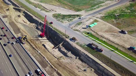 Tight-Aerial-Orbit-around-crane,-excavator,-and-dump-trucks-at-a-Construction-Site-in-Lehi,-Utah-Building-Interstate-15-I15-at-the-Point-of-the-Mountain-Lehi-Corridor-Traffic-Highway-Freeway-2017