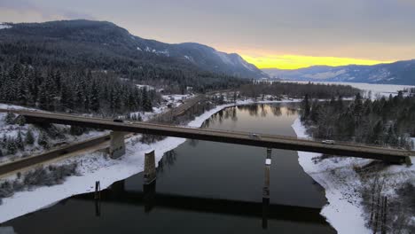 drone flyover of snowy thompson river and highway 1 with sunset sky in the background