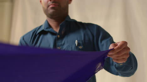 close up studio shot of sikh man folding fabric for turban against plain background 2