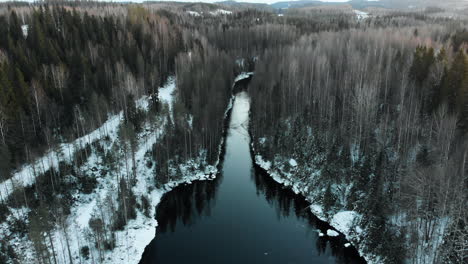 Aéreo,-Descendente,-Inclinado-Hacia-Abajo,-Disparo-De-Dron,-Sobre-Un-Río,-En-Un-Bosque-Sin-Hojas,-Primera-Nevada-En-El-Suelo,-Cerca-De-Joensuu,-Karelia-Del-Norte,-Finlandia