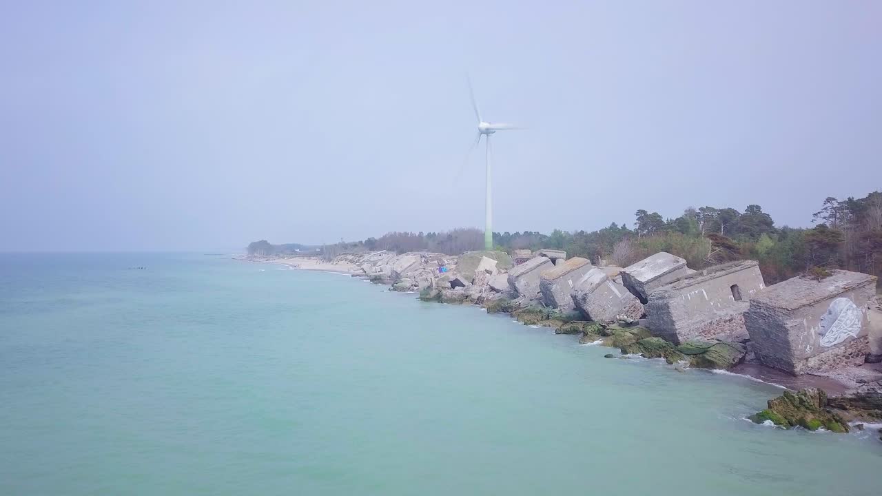 라트비아 리파야의 발트해 해변에 있는 카로스타 북부 요새에 있는 버려진 해변 요새 건물의 공중 전망, 화창한 날 잔잔한 바다, 광각 드론 샷이 앞으로 이동