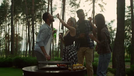 playful women feeding guys on backyard. guys tasting bbq french beans outside