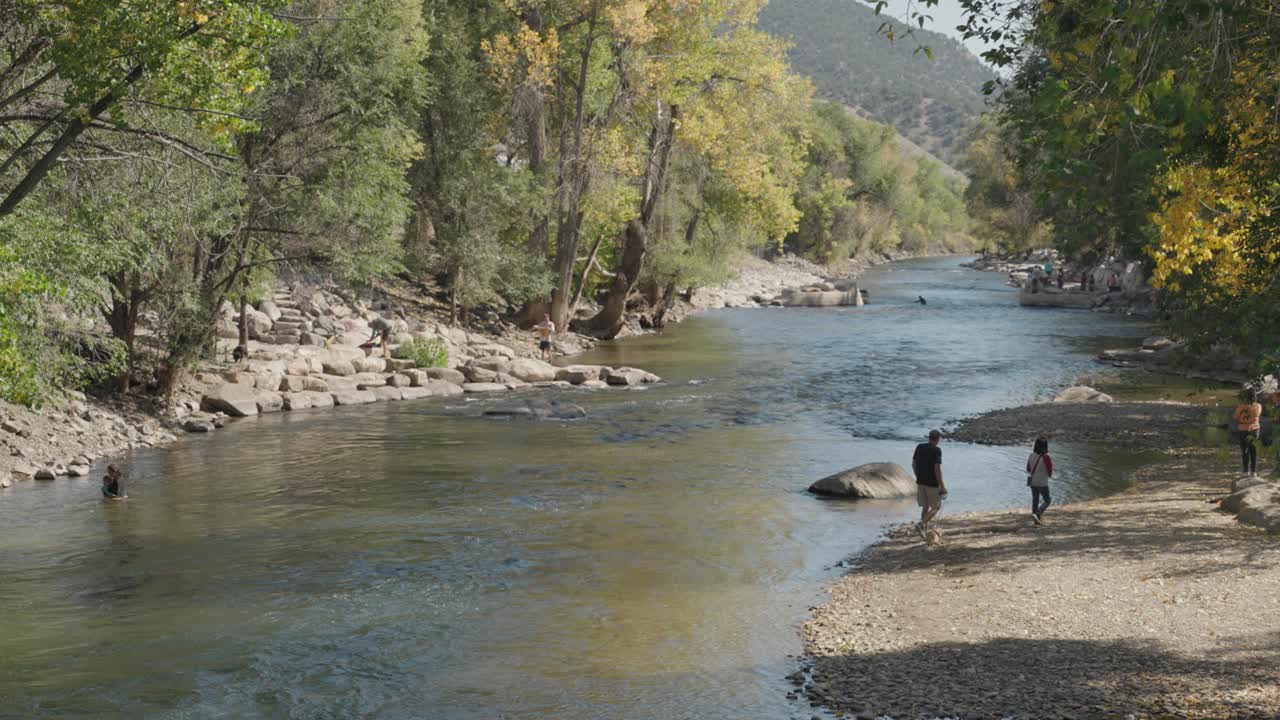 A scenic view of a river surrounded by trees and people enjoying the outdoors