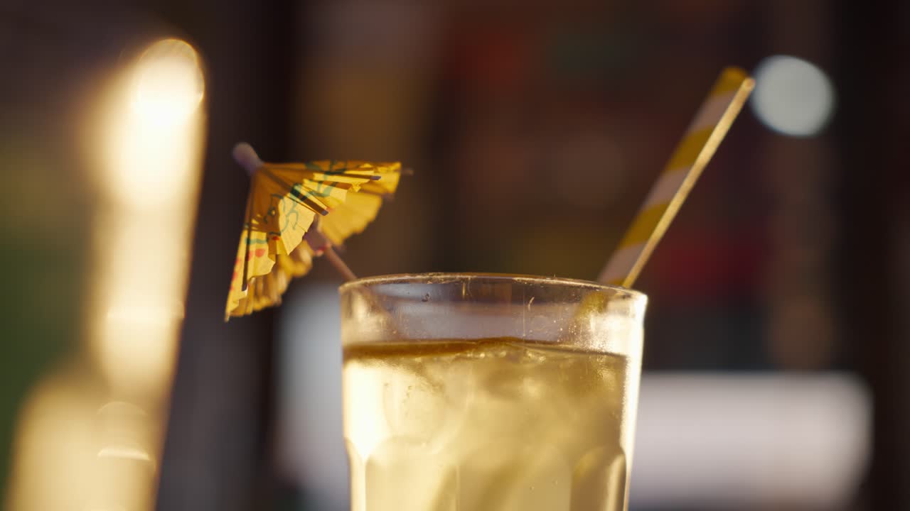 Close-up of a Refreshing Yellow Cocktail with Ice and a Paper Umbrella