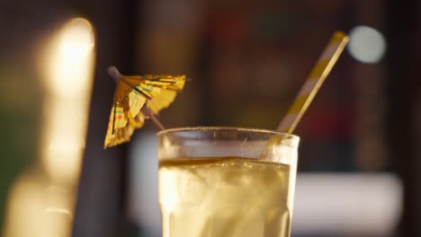 close-up of a refreshing yellow cocktail with ice and a paper umbrella