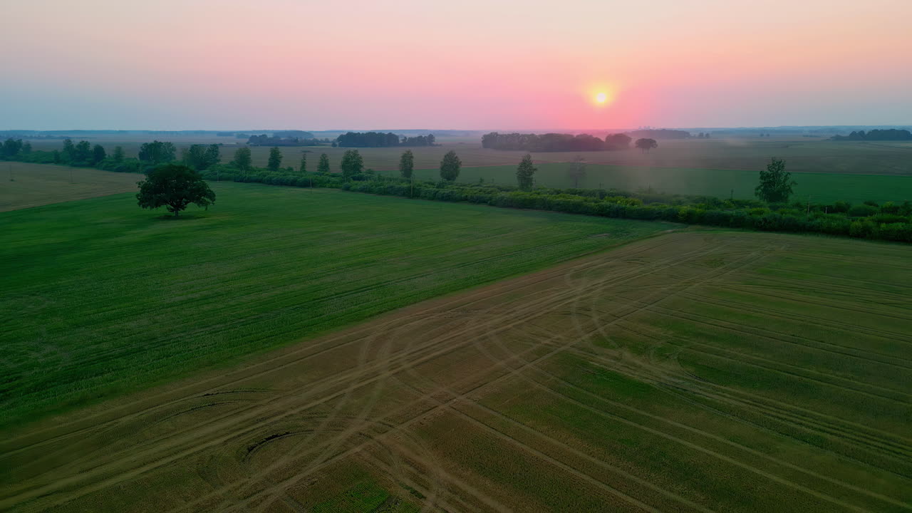 дрон летит над трактором с закатом солнца на горизонте