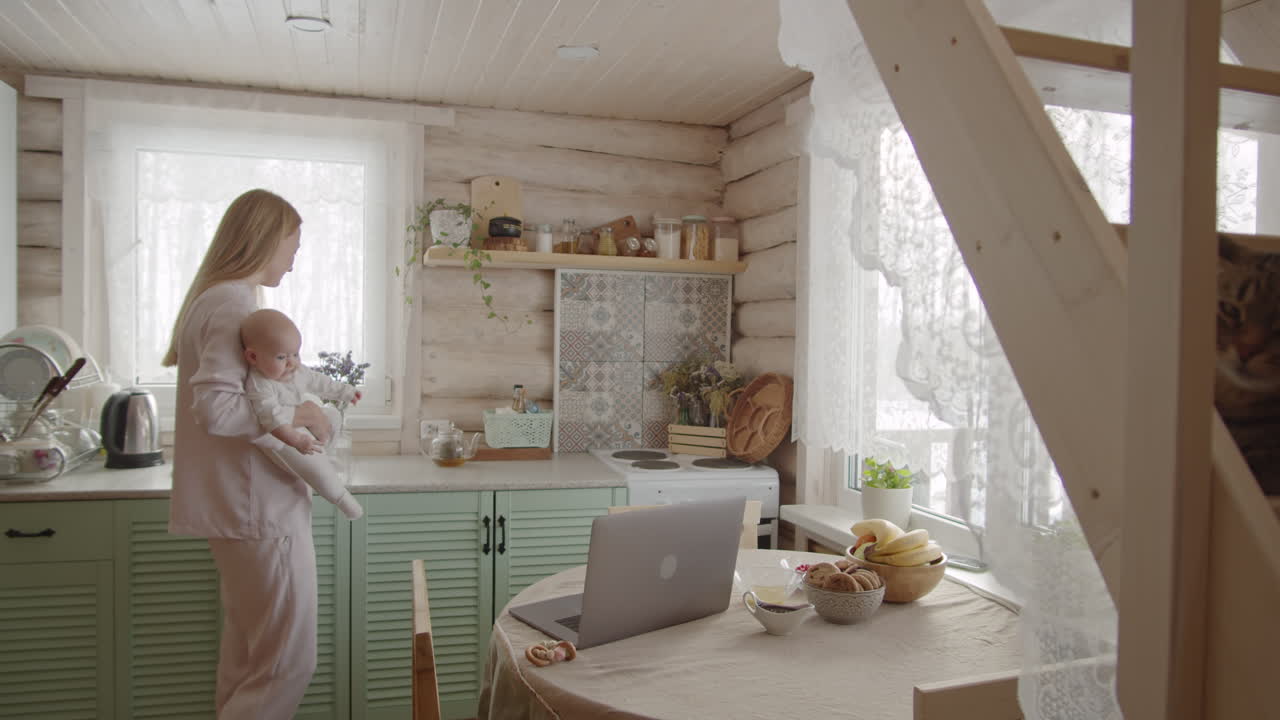 mamá trabajando con el bebé en la cocina