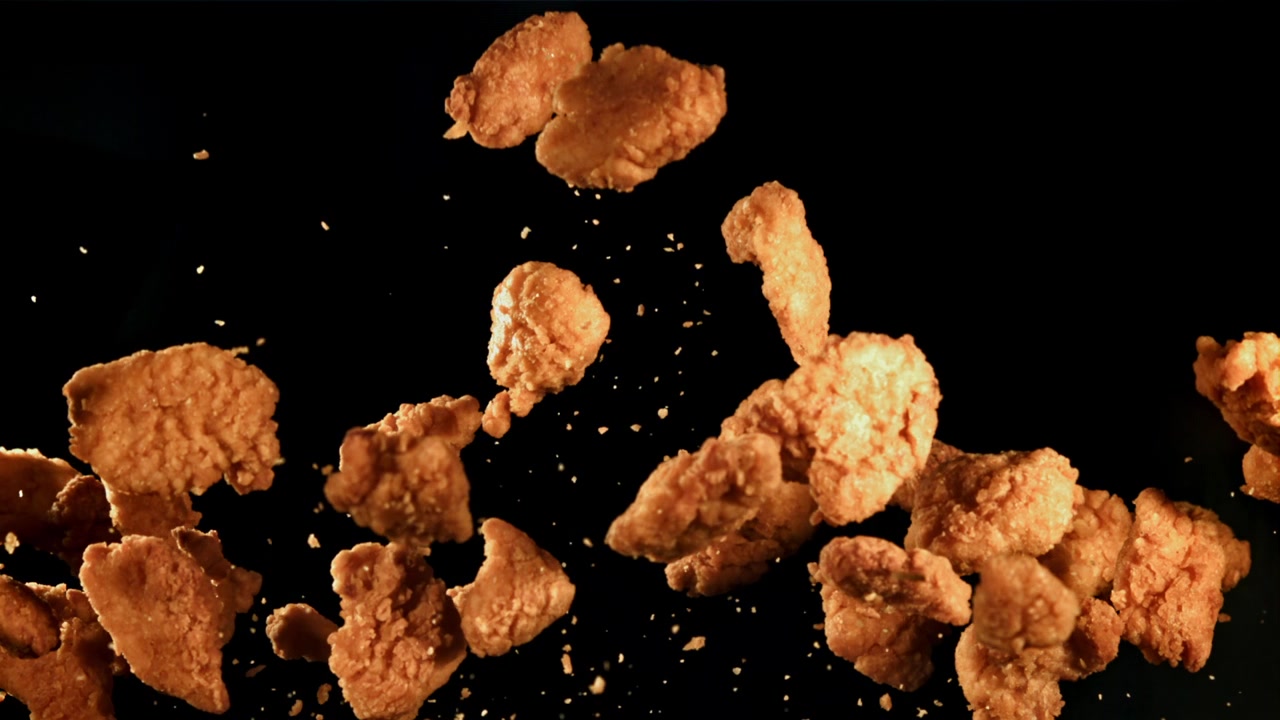 Nugget Ayam Goreng Renyah Jatuh Perlahan dengan Latar Belakang Hitam