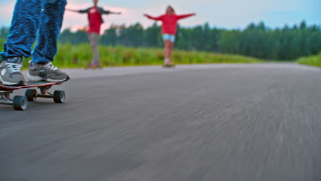 Vista-De-Los-Pies-De-Un-Niño-Patinando-En-La-Carretera,-En-El-Fondo-Un-Niño-Y-Una-Niña-Patinando