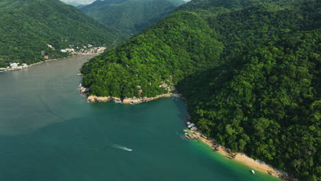 aerial view backwards, revealing a motorboat in front the exotic coastline of puerto vallarta, mexico