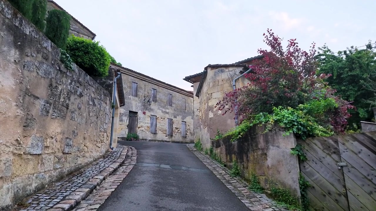 Una telecamera con angolazione bassa avanza attraverso un tranquillo vicolo storico con muri in pietra.