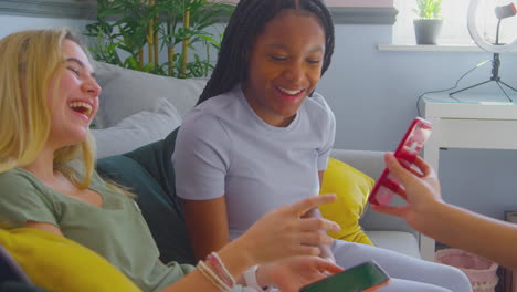 grupo de amigas adolescentes multiculturales con teléfonos móviles pasando el rato en el dormitorio en casa