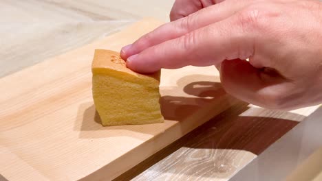 hand slicing bread on wooden board