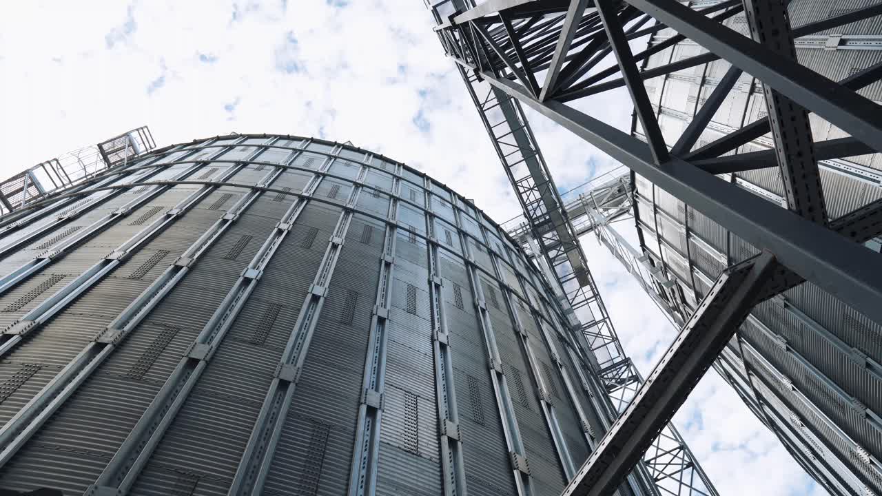 Aluminum containers on sky background. Metal tanks for the storage crop. Large elevators for farming. Exterior of agricultural plant