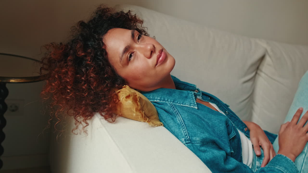 Ung kvinde sover og vågner på sofaen