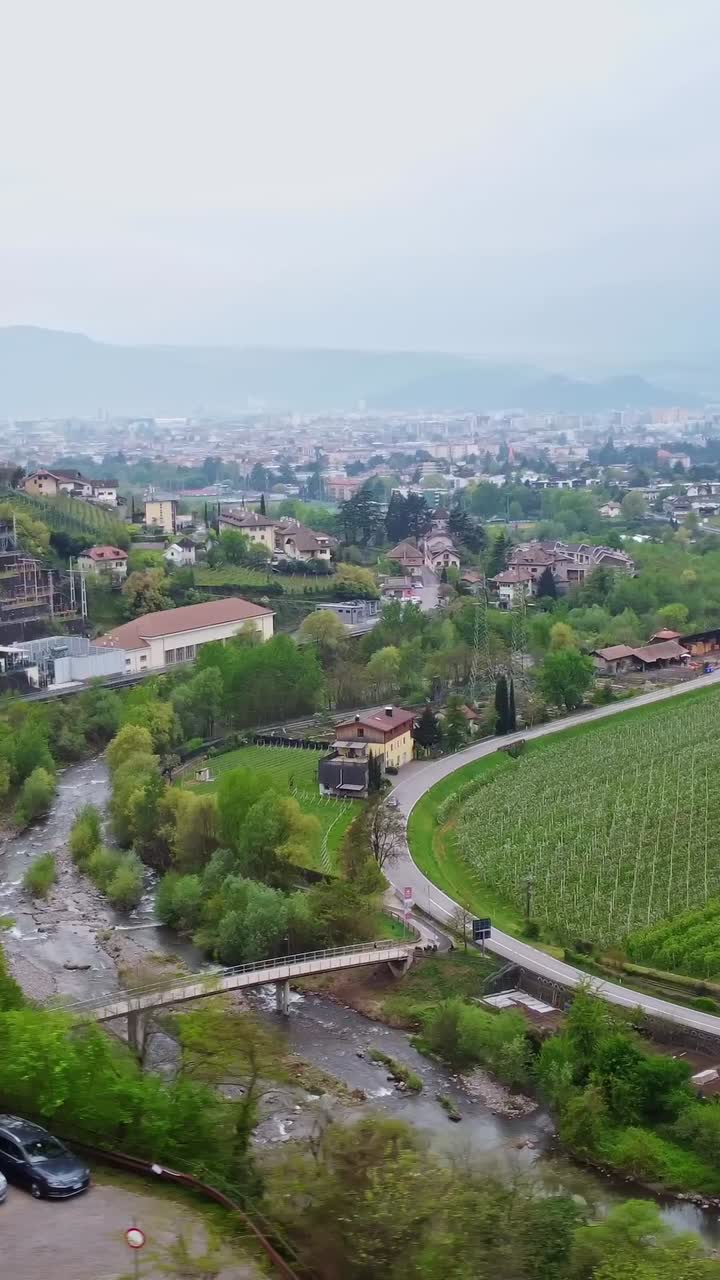A vertical view of terraced vineyards, apple orchards, and Alpine buildings near Bolzano in South Tyrol.