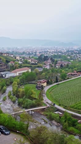 a vertical view of terraced vineyards, apple orchards, and alpine buildings near bolzano in south tyrol.
