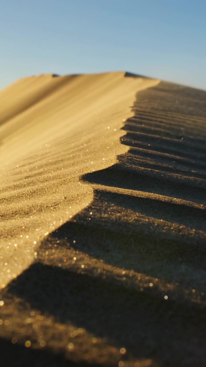 Video verticale: Telecamera in panoramica che rivela una cresta di duna di sabbia tra le dune, mostrando la texture della sabbia increspata.