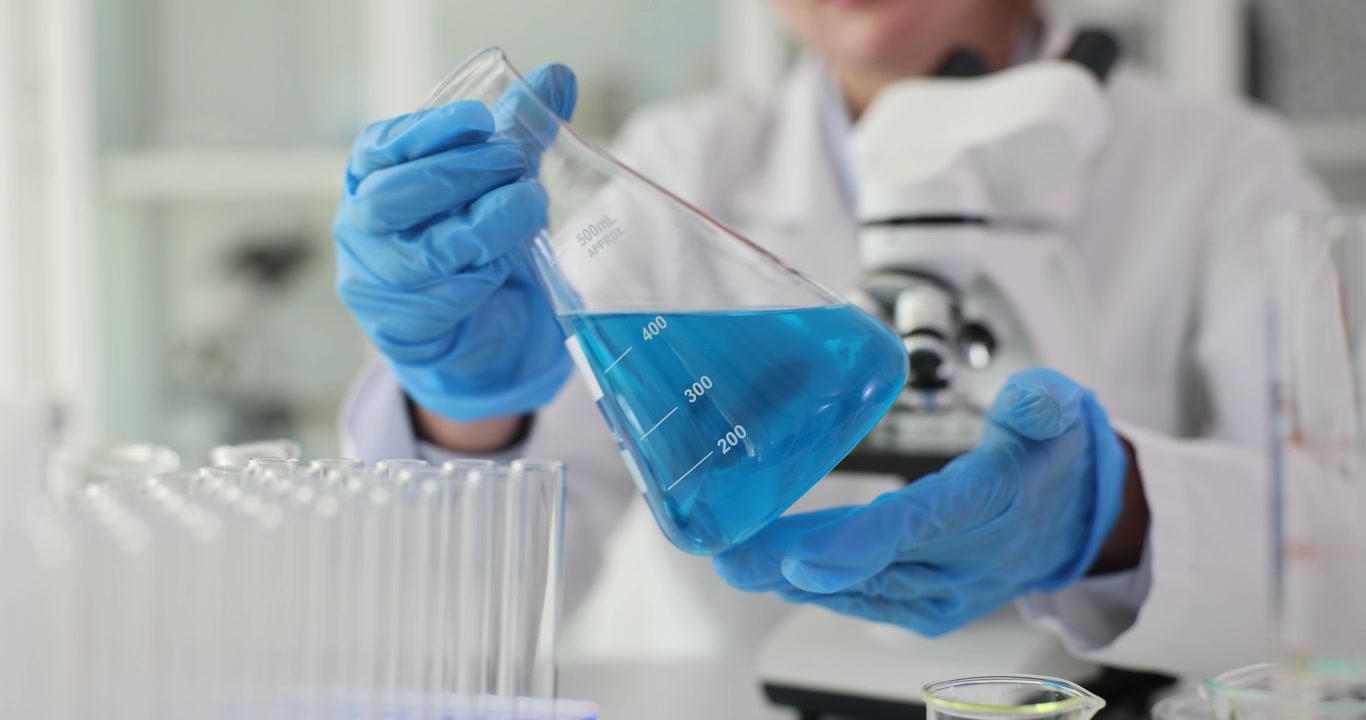 Chemist tilts beaker filled with vibrant blue liquid reagent