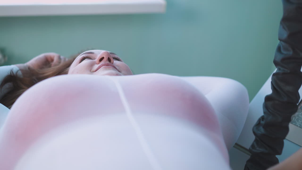 ⁇ 한 여자가 클리닉에서 배 진공 롤러 마사지를 받고 있습니다.