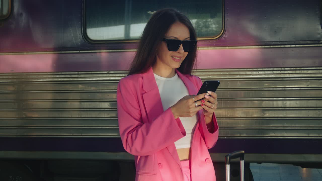 Donna alla stazione ferroviaria che usa il telefono