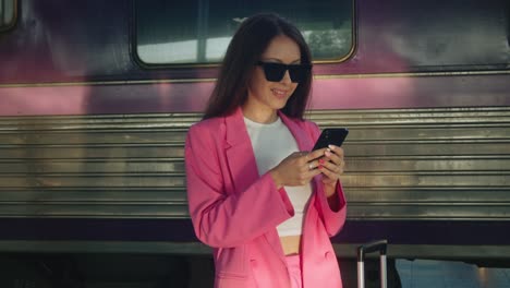 mujer en la estación de tren usando el teléfono