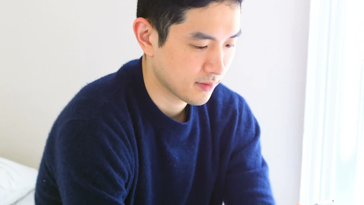 침실 4k에서 침대에 휴대 전화를 사용하는 남자