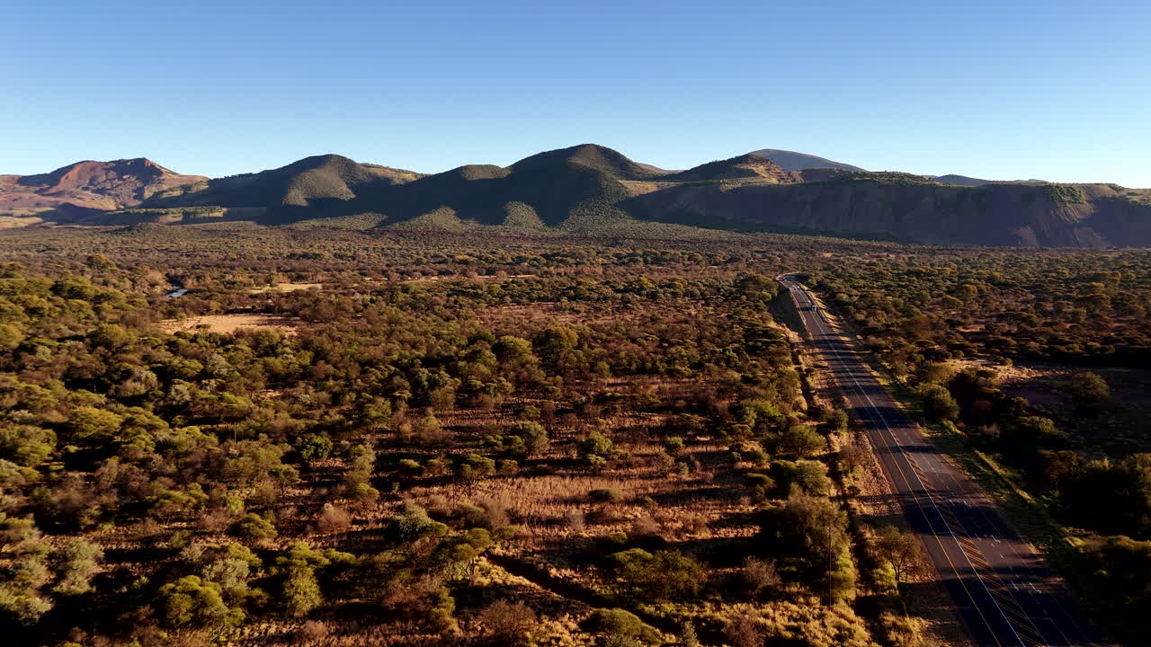 Open tar road through rural South African bushveld in early morning, aerial