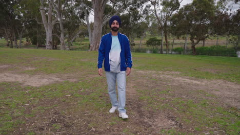 indian punjabi sikh man walking in the park while looking at camera