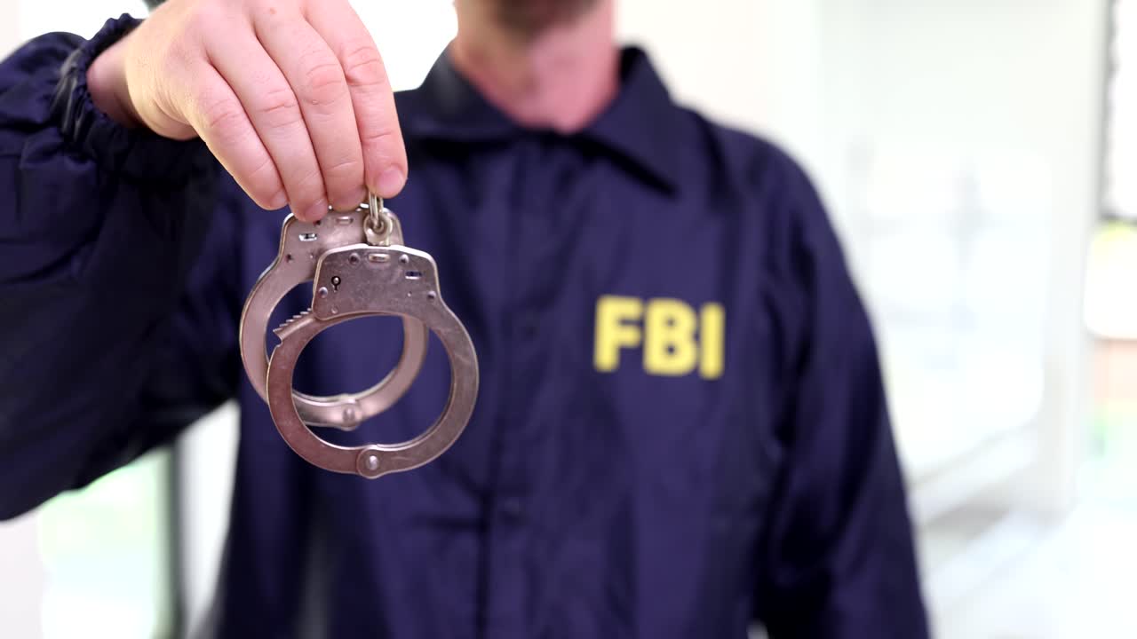 Agente FBI in uniforme che tiene le manette, primo piano, filmato 4K