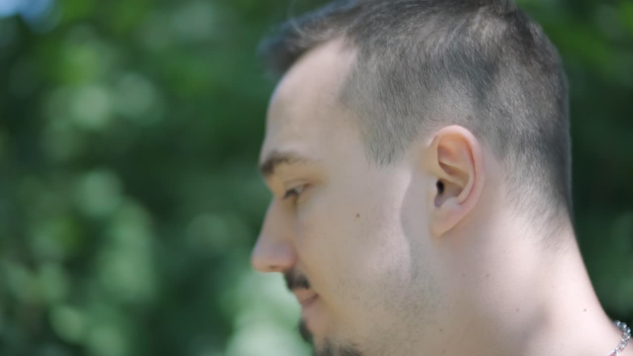 молодой человек идет с гитарой по улице возле леса