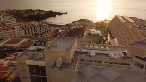 Luftaufnahme-Des-Sonnenuntergangs-Auf-Der-Insel-Teneriffa,-Strand-Los-Gigantes-Arena,-Drohnenflug-über-Einem-Wohngebiet-Mit-Hotel-Und-Unterkünften,-Die-Für-Den-Sommerurlaub-Vermietet-Werden-Können