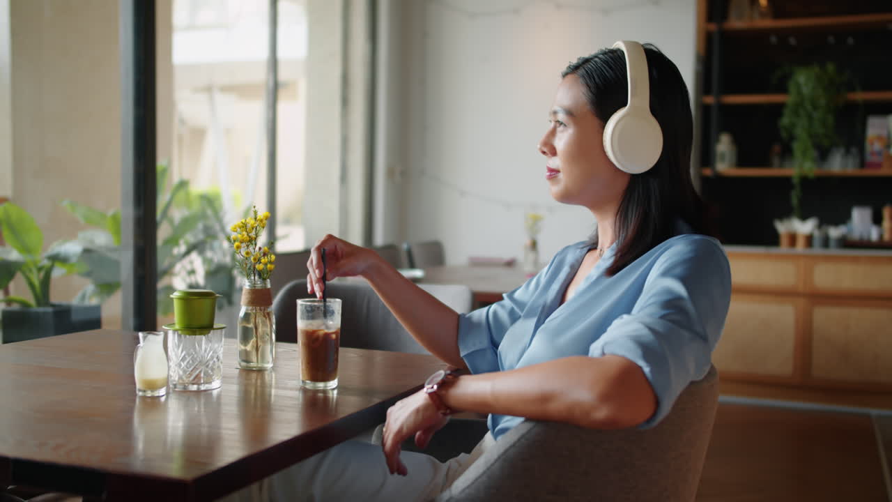 Asian Businesswoman in Headphones Having Coffee on Breakfast in Cafe