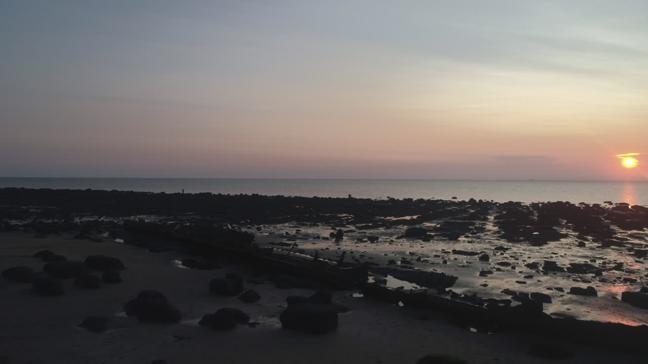 un dron aéreo bajo disparó sobre una playa de arena con rocas y peñascos y un naufragio en la hermosa e impresionante puesta de sol en old hunstanton north norfolk, reino unido