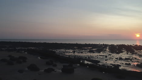 Un-Dron-Aéreo-Bajo-Disparó-Sobre-Una-Playa-De-Arena-Con-Rocas-Y-Peñascos-Y-Un-Naufragio-En-La-Hermosa-E-Impresionante-Puesta-De-Sol-En-Old-Hunstanton-North-Norfolk,-Reino-Unido