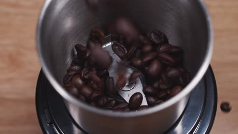 coffee beans pour out from glass jar into coffee grinder machine