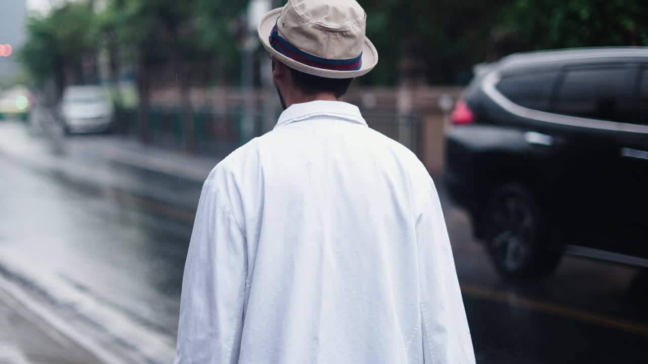 Uomo che cammina su una strada piovosa con delle borse