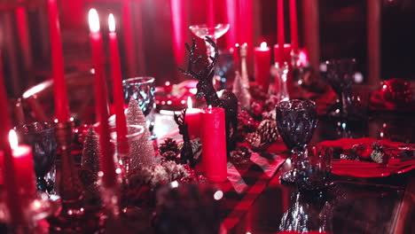 christmas table decoration in red colors. festive table with glasses and red candles. beautiful dinner table with shiny seasonal decorations in winter.