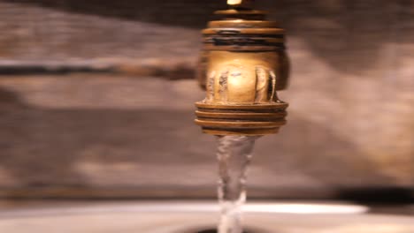 close-up of an old brass faucet with water flowing