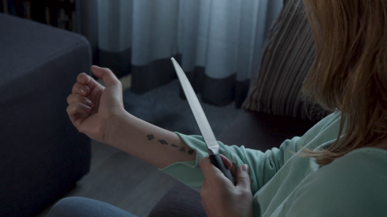 muñeco de mujer temblorosa enrollándose la manga y apuntando con un cuchillo a su muñeca para suicidarse