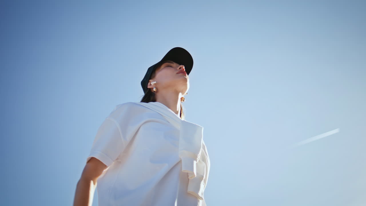Meditative woman exercising nature stretching arms wearing cap closeup