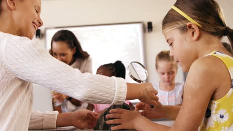 niños de la escuela usando lupa sobre la roca