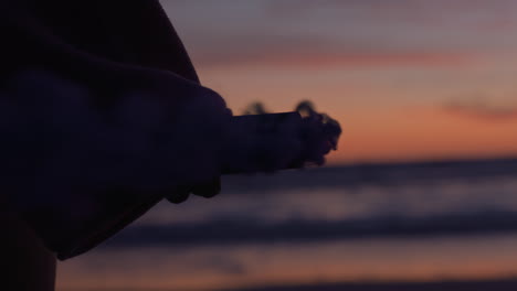 Cerrar-Mujer-Encendiendo-Granadas-De-Humo-En-La-Playa-Al-Atardecer-Con-Chispas