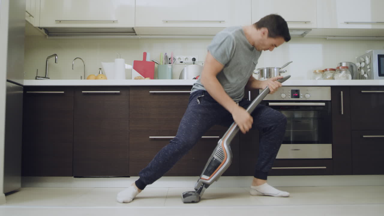 Happy husband cleaning floor at modern kitchen.