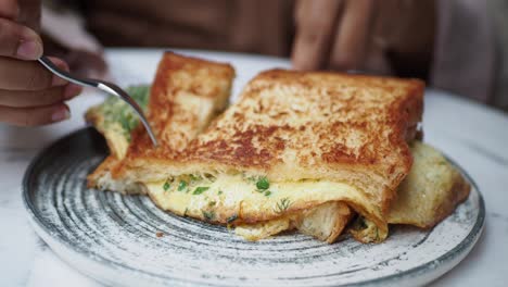 close-up of a person eating a delicious egg sandwich for breakfast