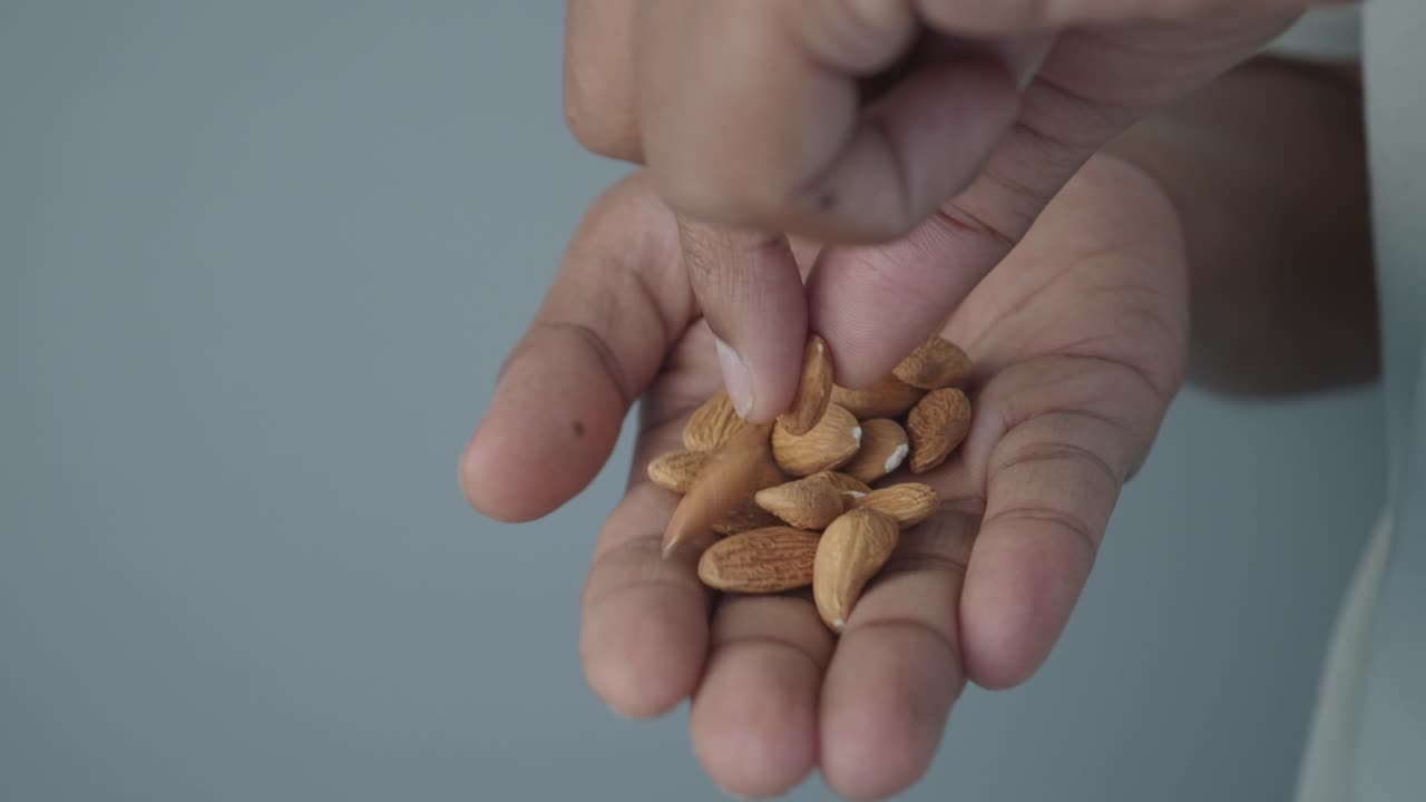Close Up of Hand Holding and Picking Up Almonds
