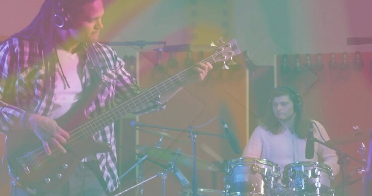 Chitarrista che suona un riff che scatena una jam session della band in uno studio musicale con onde animate che si sincronizzano con i battiti.