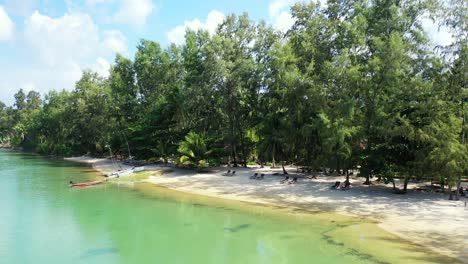 Secluded-sandy-beach-with-sun-beads-and-tropical-trees,-azure-ocean-water