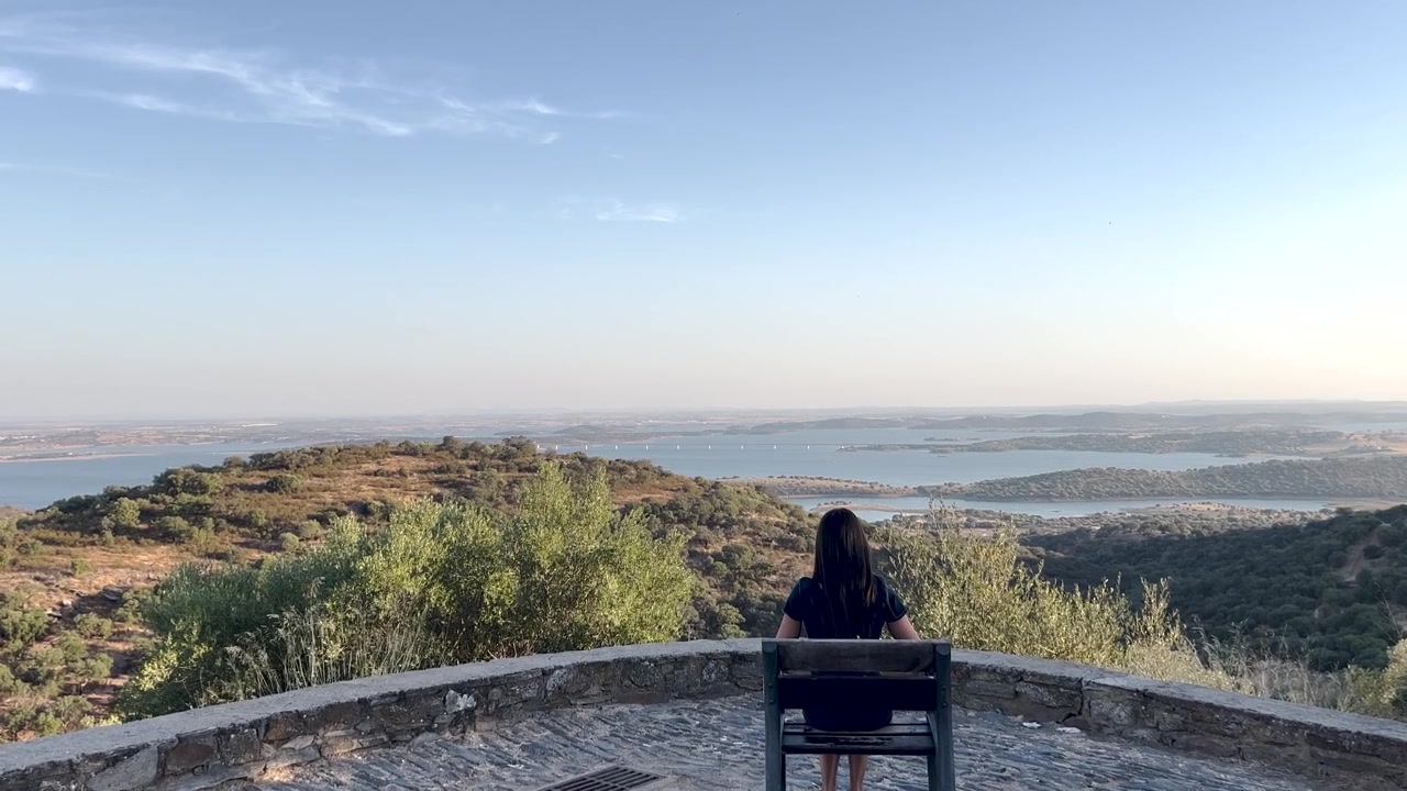 Beautiful young brunette woman overlooking Portugal Atlantic ocean coast viewpoint