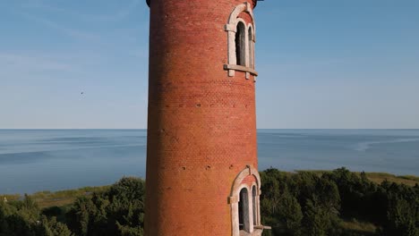 ascending aerial drone flight over lost place lighthouse at the coast of baltic sea - country side of estonia in europe - nature helicopter flyover establishing shot summer 2022